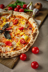 Pizza made on wood and Kraft paper, around tomatoes, herbs and garlic. Lunch prepared at home