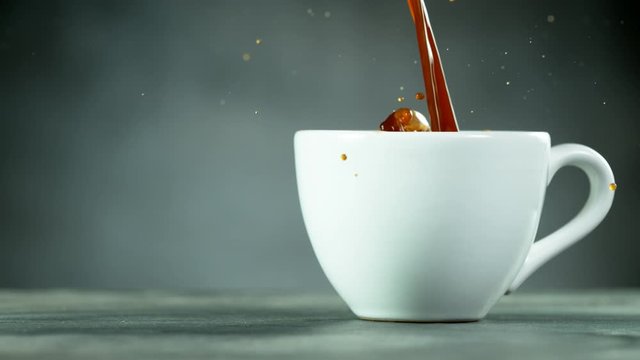 Super slow motion of pouring coffee into cup with copy space. Filmed on high speed cinema camera, 1000fps