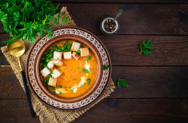 Pumpkin soup in a bowl served with croutons and parsley. Vegan diet soup. Vegetarian food. Top view, overhead