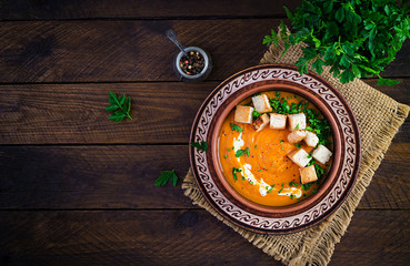 Pumpkin soup in a bowl served with croutons and parsley. Vegan diet soup. Vegetarian food. Top view, overhead