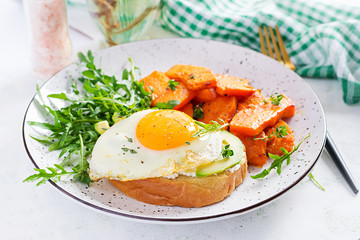 Healthy breakfast. Avocado sandwich with fried egg and fried sliced pumpkin with arugula for healthy breakfast or snack.