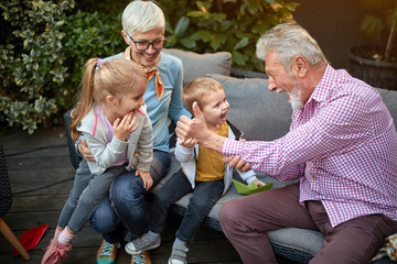 grandparents playing with their grandchildren in the backyard - obrazy, fototapety, plakaty