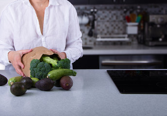 Caucasian Woman Holding Brownpaper Bag Full of Green Vegetables 