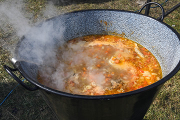 Very large cauldron cooking food during campfire. Cooking in a pot on the fire. Camping concept