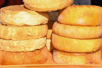 A variety of wheels of cheese seasoned with herbs for sale at the deli counter in the supermarket.
