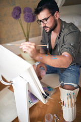 young male artist thoughtfully paint