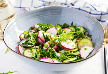 Vegetarian vegetable salad of radish, cucumbers, arugula and green onions. Healthy  vegan food.