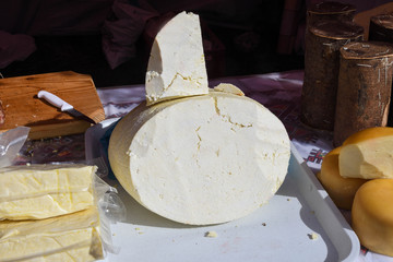 A variety of wheels of cheese seasoned with herbs for sale at the deli counter in the supermarket.