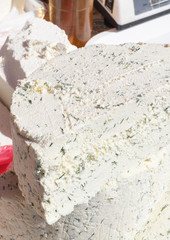 A sliced piece of cheese with dill and spices, for sale on counter top, during food festival.