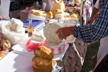 A sliced piece of cheese with dill and spices, for sale on counter top, during food festival.