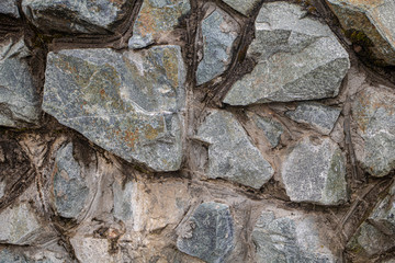 Stones of different sizes of gray and bluish color glued together with cement