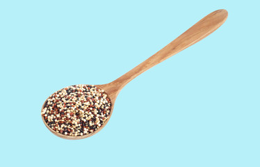 Quinoa in wooden spoon isolated on blue background, health care concept