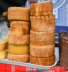 A variety of wheels of cheese seasoned with herbs for sale at the deli counter in the supermarket.