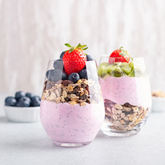 Chia seeds pudding with granola, blueberry and strawberry in glasses. Yogurt with chia seeds, berries, kiwi and muesli for healthy breakfast, copy space