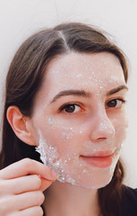 Beautiful young woman with healthy skin removes purifying transparent peel off mask with shiny sparkling star glitter from her face. Trendy cosmetic beauty procedure.Skin care concept.