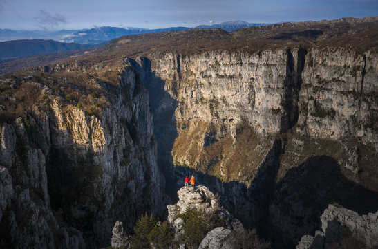 Couple standing on the top of mountain rocks on Vikos Gorge, aerial photo by drone