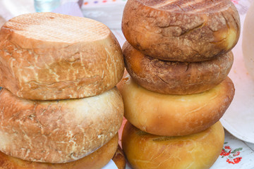 A variety of wheels of cheese seasoned with herbs for sale at the deli counter in the supermarket.
