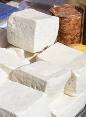 A variety of wheels of cheese seasoned with herbs for sale at the deli counter in the supermarket.