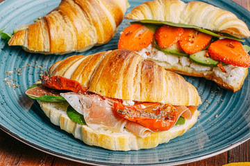 The concept of a hearty and tasty breakfast of fresh classic croissants with a variety of toppings from ricotta jamon avocado, strawberries, sun-dried tomatoes, and French mustard.