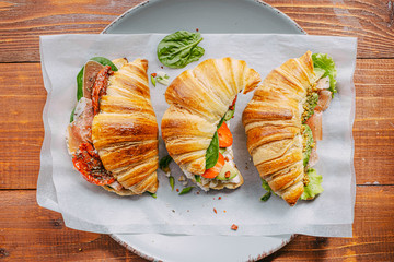 The concept of a hearty and tasty breakfast of fresh classic croissants with a variety of toppings from ricotta jamon avocado, strawberries, sun-dried tomatoes, and French mustard.