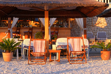 Cafe on sea coast with chairs, tables and sun loungers. Vacation, tourism and resort in sunny summer.