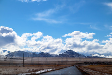 Plateau, hoogspanningstransmissietoren, blauwe lucht en witte wolken, ijsmeer en verre Shishapangma Peak