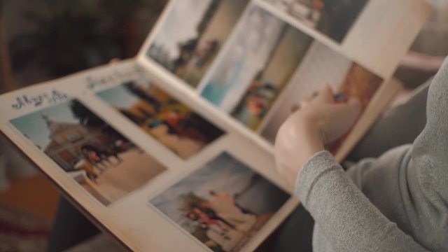 Woman is looking at old photo album at home. A woman recalls the past, as it was before.