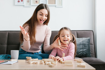 Mom and daughter play a board game in the living room.