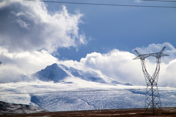Plateau, hoogspanningstransmissietoren, blauwe lucht en witte wolken, ijsmeer en verre Shishapangma Peak