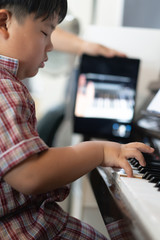 A boy is learning piano online with a tablet by the social network .