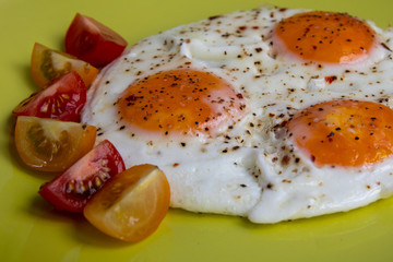 Fried eggs with cherry tomatoes on a plate. Tasty breakfast