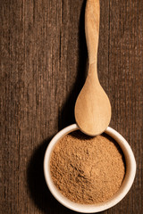 Finely ground cinnamon in a white ceramic bowl on a dark background