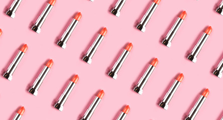 Pattern made from lipsticks on pink background.