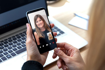 Two young woman talking to each other through a video call on a smartphone. Blonde woman having a video chat with other girl on mobile phone.