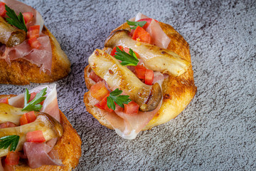 Bruschetta with proscuitto ham, tomatoes and King oyster mushroom. Iitalian style food