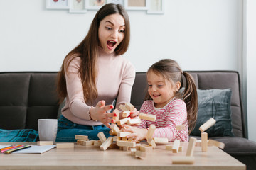 Mom and daughter play a board game in the living room.