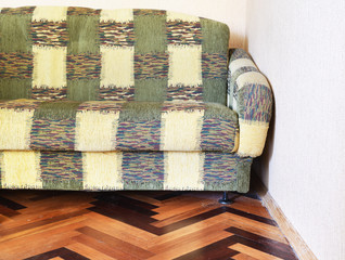 Upholstered furniture sofa on the floor in a Soviet apartment, interior in the style of the 90s. Old design in the house.