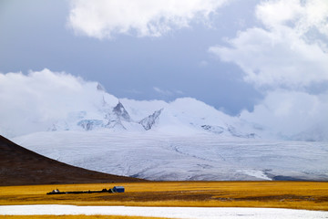 Sunny after the snow, the hut on the pasture, the snowy mountains in the distance, the blue sky and...