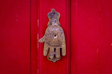 Hand of Fatima, a typical Moroccan design, as a door knocker on a red wooden front door