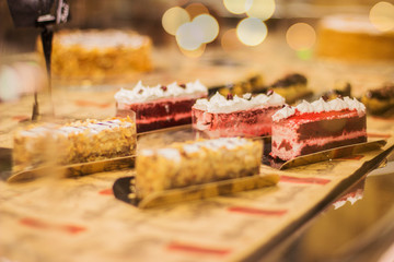 Closeup of multiple sweet cakes on shopping window of pastry shop. Consumption of confectionery, pastry sweet products. Showcase of sweet food at restaurant or patisserie cafe.