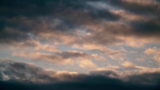 timelapse d'un ciel recouvert de nuage de couleur orange et Bleu passant par de l&eacute;g&egrave;re touche de rose, mais recouvert par un l&eacute;ger voile sombre laissant pr&eacute;sager que la pluie  va faire son apparition.