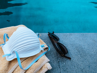 Fototapeta na wymiar Medical face mask for protection against the Corona Virus (COVID-19) laying beside a pool 