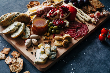 a set of beautiful and expensive products on a wooden Board cheese honey bread nuts and dried fruits and cherry tomatoes sliced sausages and olives