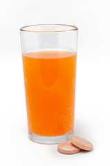 soluble effervescent multivitamins near a glass with vitamin in water on a white background