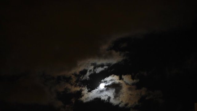 the moon shines brightly in the night sky through the clouds