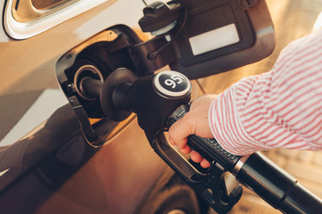 Man handle pumping gasoline fuel nozzle to refuel a car at a gas station. Close-up