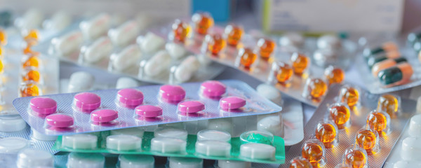 a bunch of different medical pills and capsules, blurry background