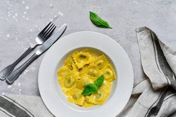 Ravioli with ricotta and spinach in a white plate on a grey stone table. Recipe of Italian pasta, gourmet lunch.  Top view , copy space , food  flat lay