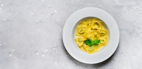 Ravioli with ricotta and spinach in a white plate on a grey stone table. Recipe of Italian pasta, gourmet lunch.  Top view , copy space , food  flat lay