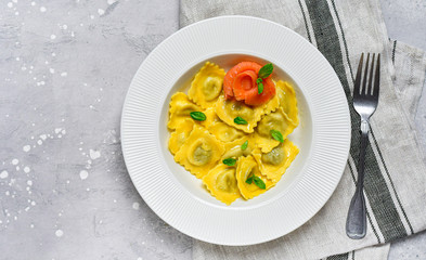 Salmon ravioli traditional Italian food with fresh basil  in a white plate on a grey stone table. Recipe  Italian cuisine, . Top view , copy space , food flat lay